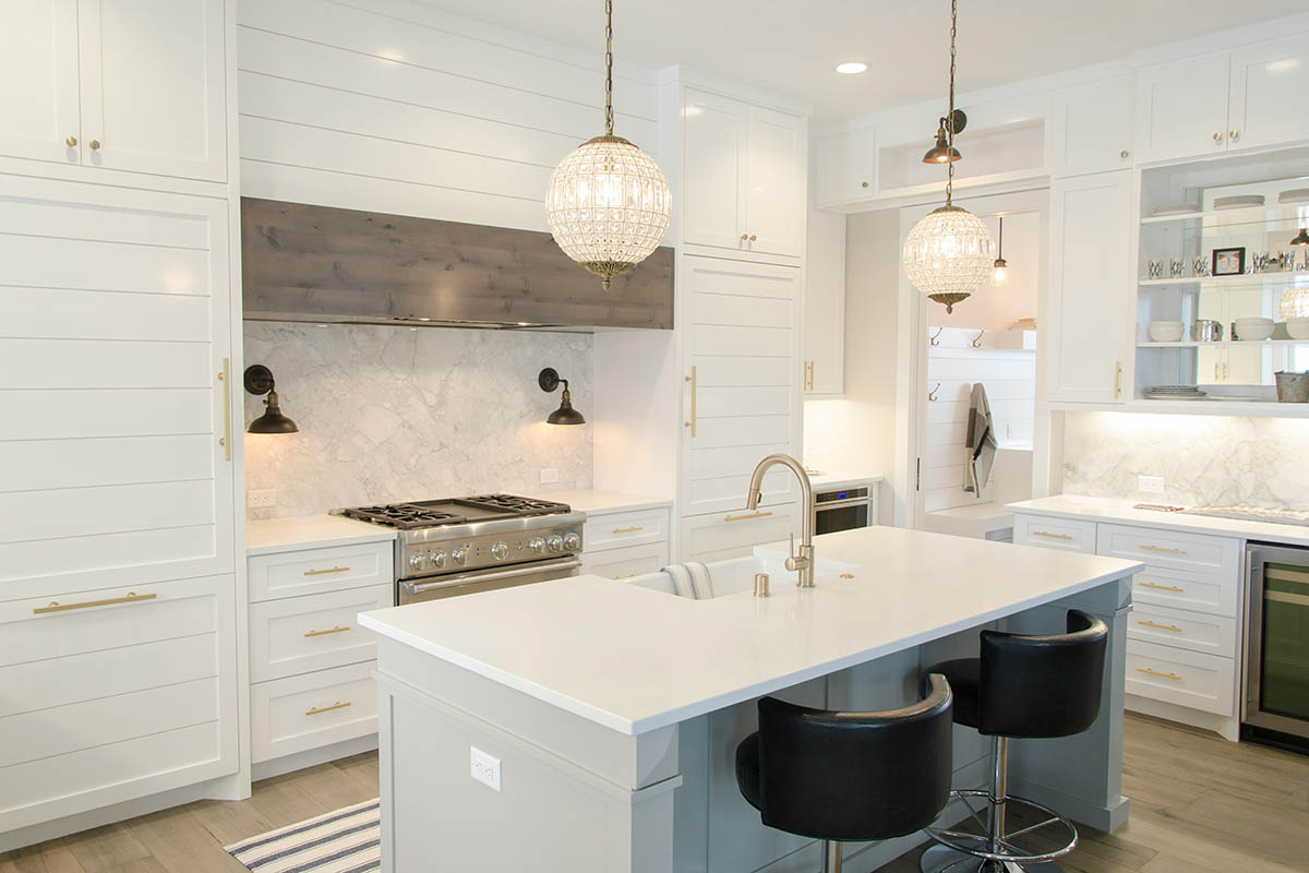 Apartment kitchen with wood style floor, white cabinets, island with sink, and stainless steel appliances.