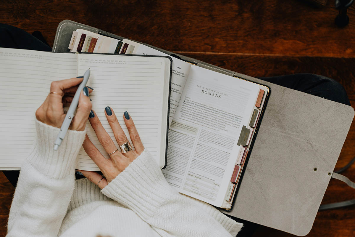Person with pen working in notebooks.